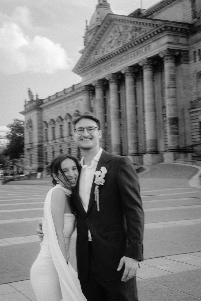 Strahlendes Brautpaar vor historischer Fassade bei Hochzeitsreportage in Leipzig